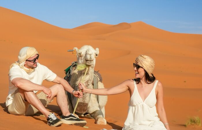 Camel caravan trekking through golden Erg Chebbi dunes at sunset during a 9 Days Desert Tour from Casablanca to Marrakech.